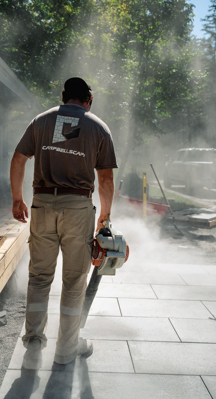 Campbellscape crew member walking across a newly finished light grey interlock patio in Almonte, Ontario