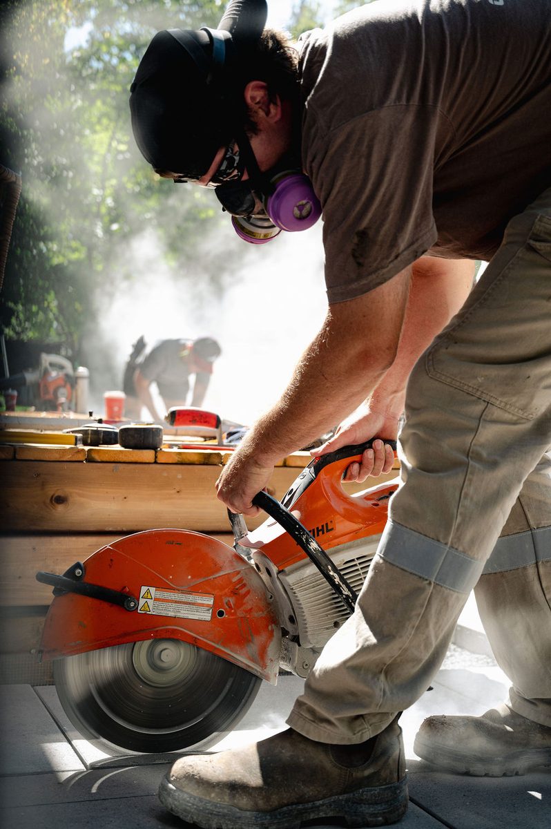 Campbellscape crew member cutting interlock pavers on site