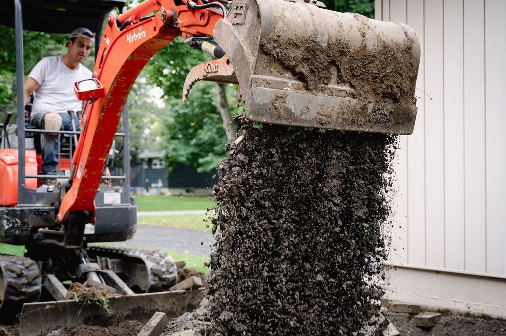 Excavator dumping a bucket of excavated soil during the tear-out