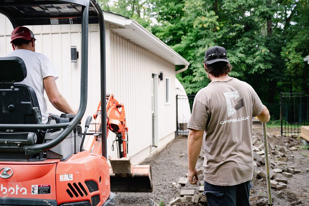 Campbellscape operator and crew member standing beside the skid steer on site