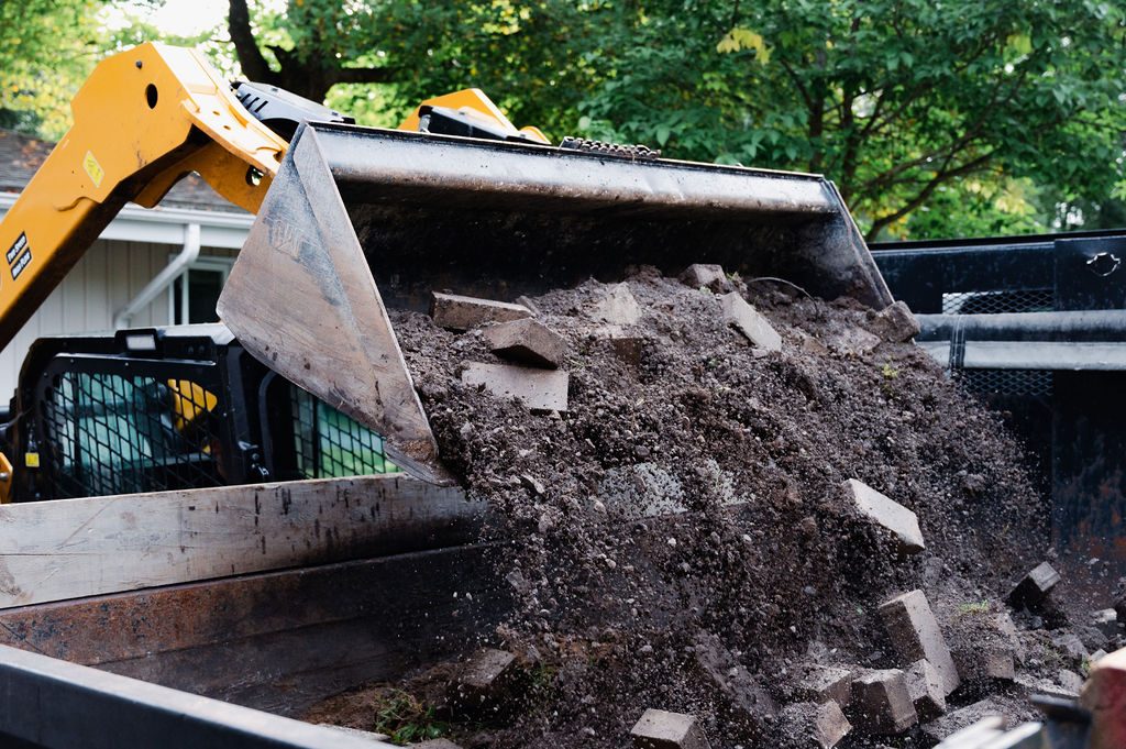 Skid steer dumping demolition debris into the truck